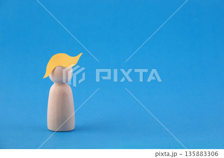 Wooden man figurine with paper yellow hair on blue background that may depicting US President Donald Trump 135883306