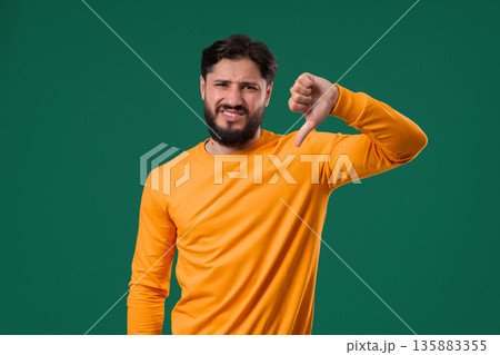 Portrait of unhappy man condemns with sign of dislike. Young millennial guy Portrait of unhappy man condemns with sign of dislike. Young millennial guy 135883355
