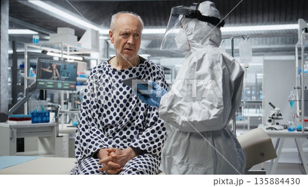 Researcher in secured lab treating infected patient in quarantine, recording virus symptoms and analyzing drug efficacy to develop a vaccine and breakthrough in medical protection. Camera A. 135884430
