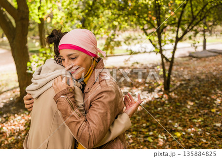 Cancer survivor mother hugging daughter in autumn park Cancer survivor mother hugging daughter in autumn park 135884825