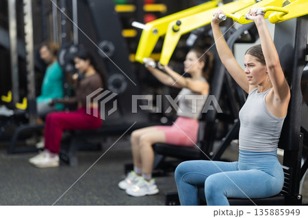 Determined young woman training upper body muscles 135885949