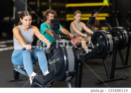 Woman doing cardio workout on rowing machine Woman doing cardio workout on rowing machine 135886114
