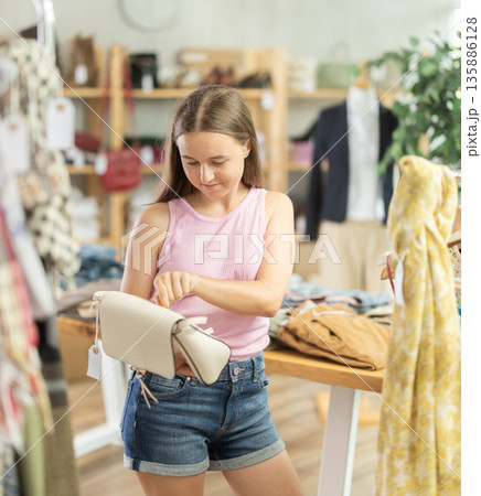 Teenager choosing a handbag in a store Teenager choosing a handbag in a store 135886128