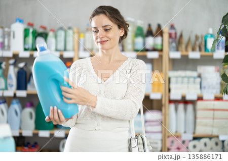 Young woman buyer chooses detergent in store Young woman buyer chooses detergent in store 135886171