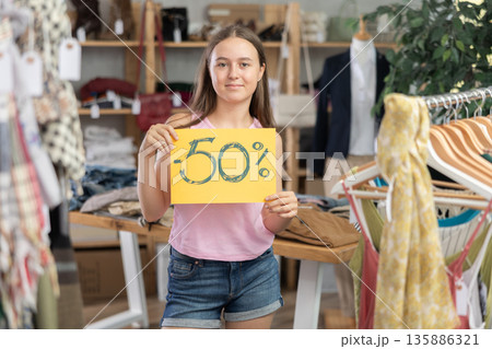 Teenage girl holding discount sign in clothing store 135886321