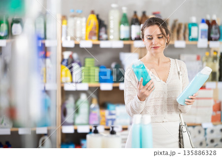 Young woman choosing shampoo or shower gel in supermarket 135886328