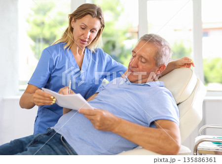 Woman doctor give senior patient medical documents for review before carrying out cosmetic procedure Woman doctor give senior patient medical documents for review before carrying out cosmetic procedure 135886361