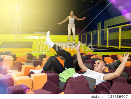 Joyful guy jumping into foam pit at indoor trampoline arena 135886407