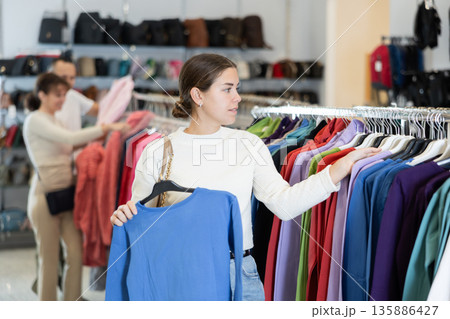 Young girl choosing blue blouse in clothing store Young girl choosing blue blouse in clothing store 135886427