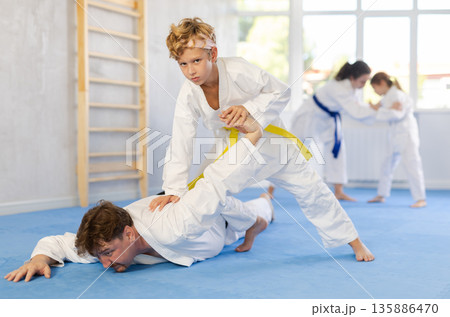 Parent with child athletes in pair conduct training battle in oriental fighting technique Parent with child athletes in pair conduct training battle in oriental fighting technique 135886470