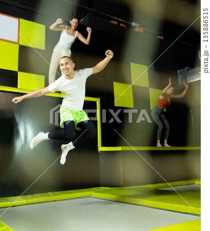 Emotional man jumping vertical and flying in trampoline sport center indoors Emotional man jumping vertical and flying in trampoline sport center indoors 135886515