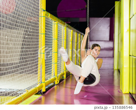 Happy girl goes down zip line at high speed in an amusement park. Storm of emotions and delight 135886546