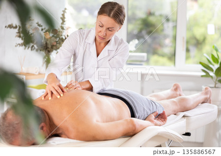 masseuse giving massage to male patient 135886567
