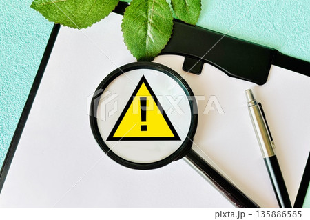 虫眼鏡と注意マークと水色バック 虫眼鏡と注意マークと水色バック 135886585