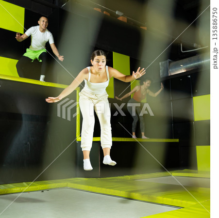 Girl acrobatic athlete jumping and exercising on trampoline indoors, modern hobby and fitness concept Girl acrobatic athlete jumping and exercising on trampoline indoors, modern hobby and fitness concept 135886750