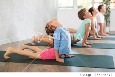Mom, dad, son and daughter perform pose dog muzzle up - cobra, Urdhva Mukha Shvanasana- Bhujangasana 135886751