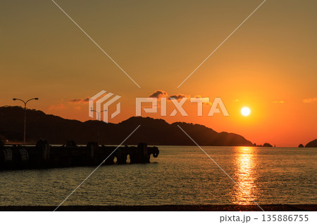 夕日に輝く瀬戸内海と八幡浜港の防波堤が織りなす静かなサンセット風景 夕日に輝く瀬戸内海と八幡浜港の防波堤が織りなす静かなサンセット風景 135886755