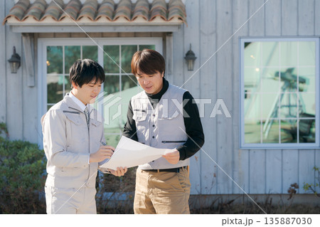 家の前で図面を見る職人たち 135887030