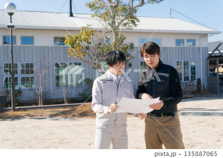 家の前で図面を見る職人たち 135887065