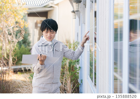 外から窓を確認する作業服の男性 外から窓を確認する作業服の男性 135888520