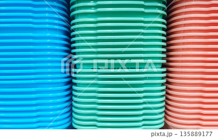 Symmetrical Stack of Blue Green and Pink Plastic Trays in Close Up 135889177