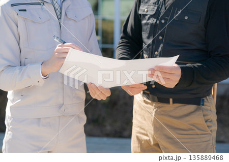 図面を見て話し合いをする職人 135889468