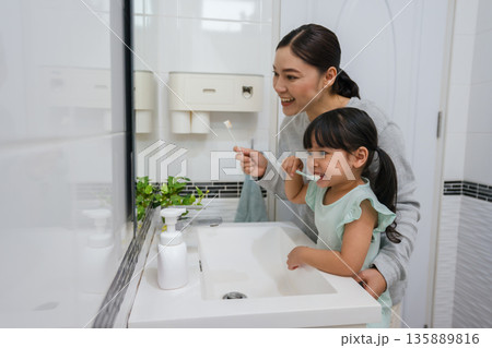 mother teaching girl child to brushing teeth in bathroom mother teaching girl child to brushing teeth in bathroom 135889816
