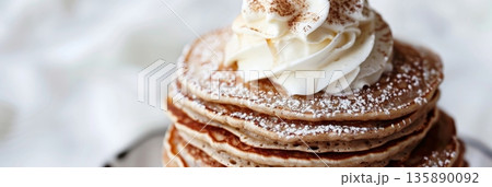 A stack of fluffy buckwheat pancakes topped with a dollop of whipped cream and a sprinkle of cinnamon sugar A stack of fluffy buckwheat pancakes topped with a dollop of whipped cream and a sprinkle of cinnamon sugar 135890092