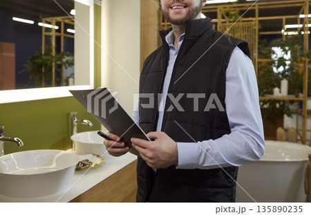 Closeup of sales consultant with clipboard in modern bathroom showroom interior Closeup of sales consultant with clipboard in modern bathroom showroom interior 135890235