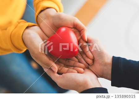 Closeup view of red heart on woman and man hands. Healthy and valentines day concept 135890315