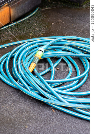 Wet pavement with garden tool, Groundskeeper prepares watering equipment on wet urban surface Wet pavement with garden tool, Groundskeeper prepares watering equipment on wet urban surface 135890845