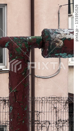 Close-up of a rusty pipe against a textured wall. 135891026