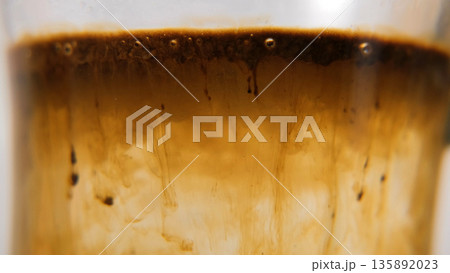 Instant coffee granules falling into hot water and dissolving. Macro shot, morning routine concept  135892023