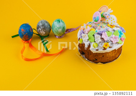 Colorful cake with Easter eggs on a bright yellow background Colorful cake with Easter eggs on a bright yellow background 135892111