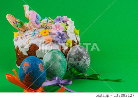 Colorful Easter cake and decorated eggs on green background Colorful Easter cake and decorated eggs on green background 135892127