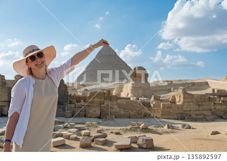 Joyful Woman s Egyptian Adventure Touching the Pyramid s Peak in Giza, Egypt 135892597