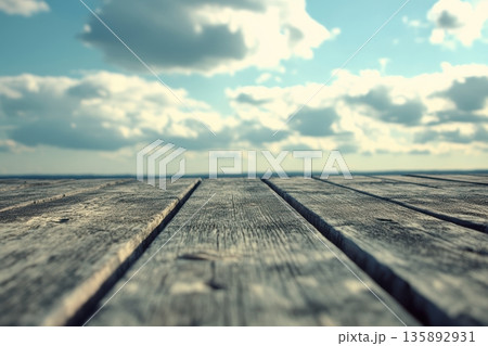 Wooden surface extends towards open sky under cloudy atmosphere 135892931