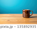 Brown ceramic coffee mug on wooden table against blue background 135892935