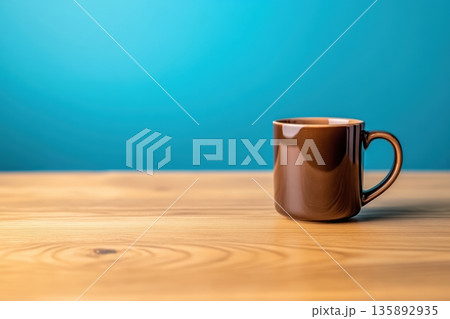 Brown ceramic coffee mug on wooden table against blue background 135892935