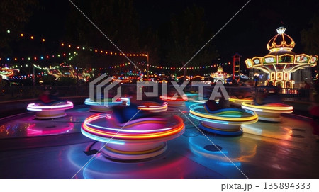 Cascading light trails follow a spinning tea cup ride adding to the whimsical atmosphere of the park Cascading light trails follow a spinning tea cup ride adding to the whimsical atmosphere of the park 135894333