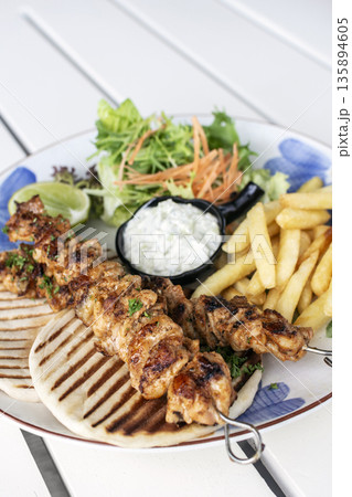 BBQ chicken skewer gyros plate on white table in mykonos restaurant greece BBQ chicken skewer gyros plate on white table in mykonos restaurant greece 135894605