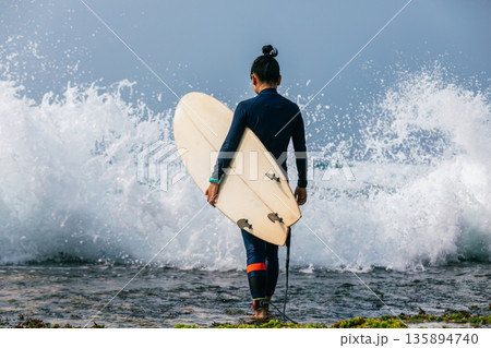 Woman surfer with surfboard going to surf the big waves 135894740