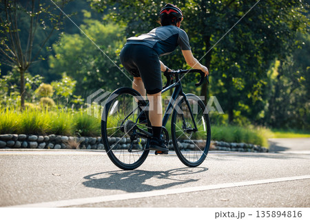 Cyclist riding bike at summer park Cyclist riding bike at summer park 135894816