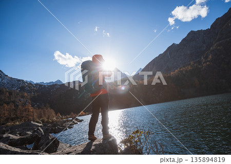Backpacking woman taking photo with a digital camera on autumn high altitude mountain top Backpacking woman taking photo with a digital camera on autumn high altitude mountain top 135894819