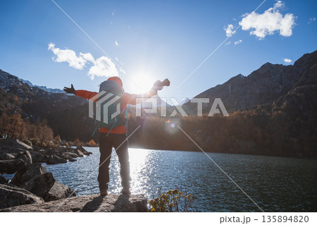 Happy backpacking woman photographer on autumn high altitude mountains 135894820