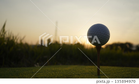 Golf ball on tee in a beautiful golf course with morning sunshine. Golf ball on tee in a beautiful golf course with morning sunshine. 135894970