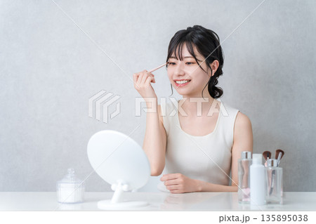 メイク中にアイシャドウを塗る若いアジア人女性 メイク中にアイシャドウを塗る若いアジア人女性 135895038