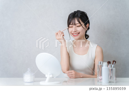 メイク中にアイシャドウを塗る若いアジア人女性 メイク中にアイシャドウを塗る若いアジア人女性 135895039