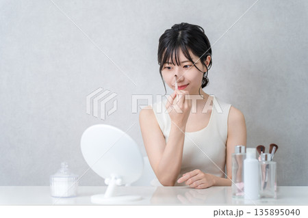 メイクブラシを使ってノーズシャドウ・ハイライトなどのメイク・化粧する女性 135895040