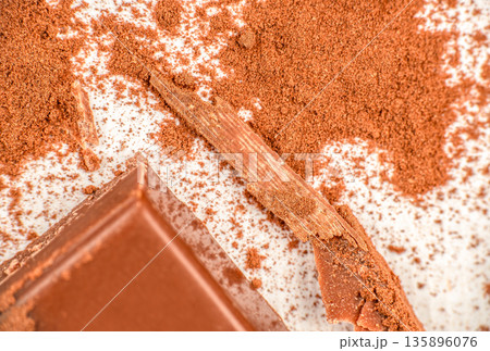 Milk chocolate pieces with cocoa powder on white background Milk chocolate pieces with cocoa powder on white background 135896076
